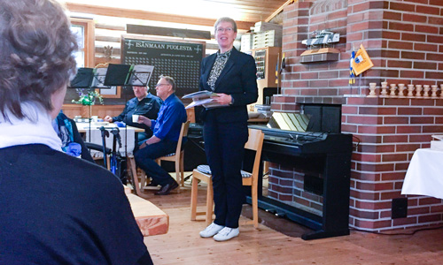 Naispuhuja seisoo ja pitää puhetta yhdistysväelle. 