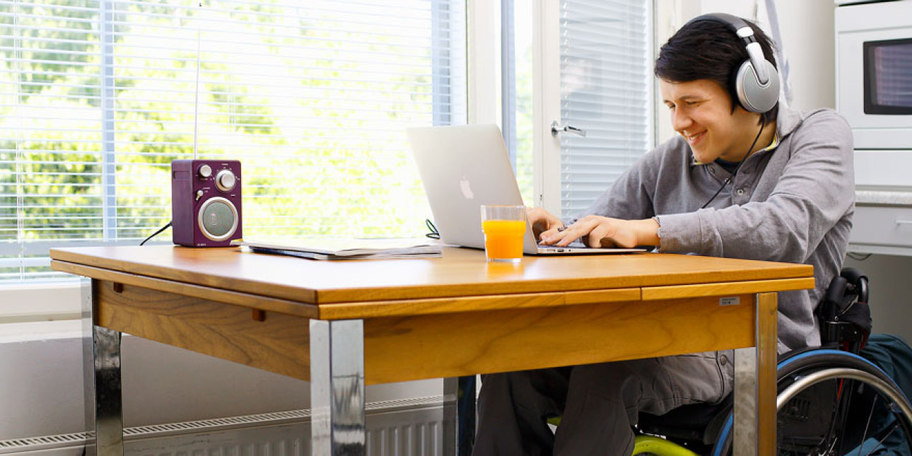 Pyörätuolissa istuva mies keittiön pöydän ääressä. Kuvituskuva.