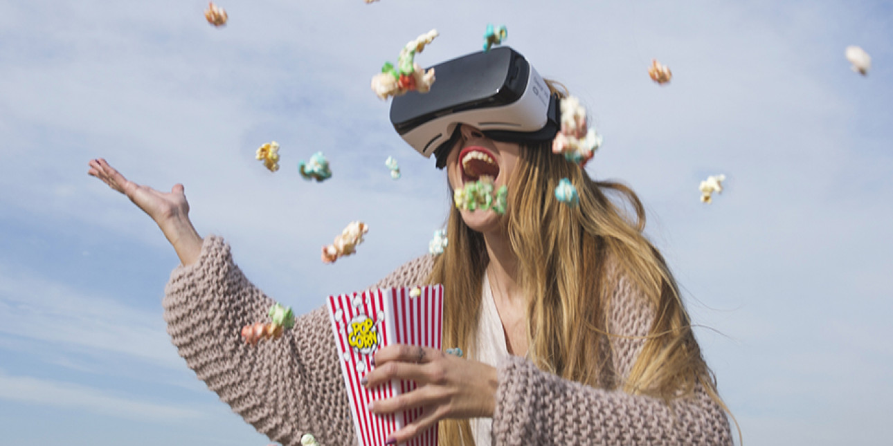 Kuvassa iloinen nainen VR lasit päässä heittelee popcorneja 