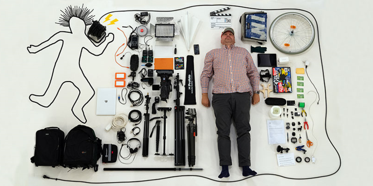 Kuvassa mies makaa lattialla erilaisten varaosien ja työkalujen keskellä. 