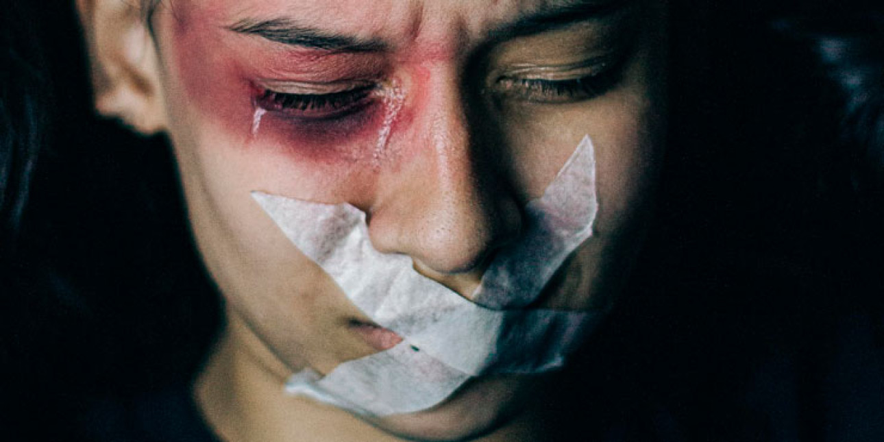 Itkuisella naisella musta silmä ja teippi suun edessä. Kuvituskuva.