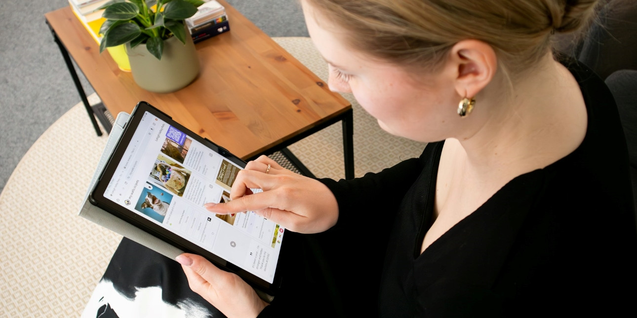 Istuva henkilö tutkii kämmentietokoneen näytöltä verkkosivua.