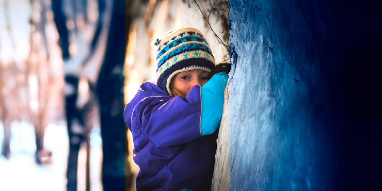 tyttö nojaa talvihaalarissa surullisena puuhun