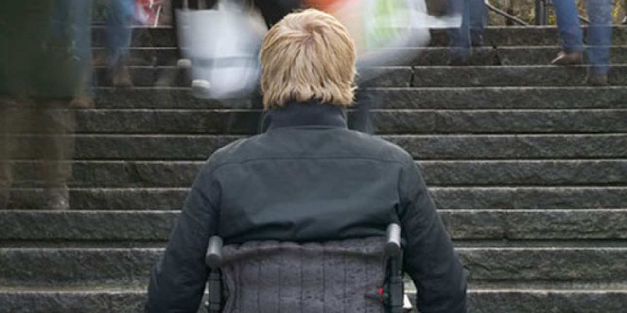 Henkilö pyörätuolissa portaiden juurella