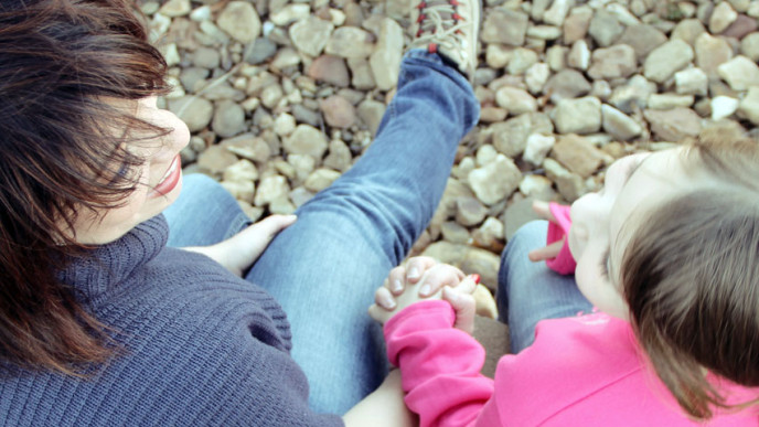 kuva äidistä ja tyttärestä käsi kädessä kivisellä rannalla