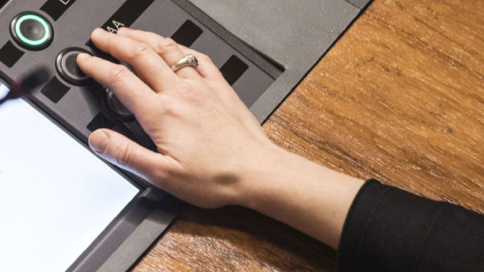 Eduskunnassa äänestysnäppiä painamassa oikea käsi jossa nimettomässä sormus.