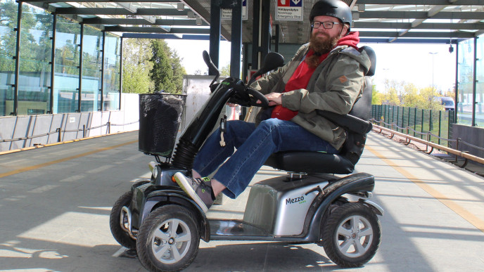 Mies sähkömopolla juna-asemalla. Kuvituskuva.