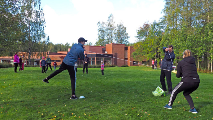 Ruohikolla aikuisia ja lapsia pelaamassa. 