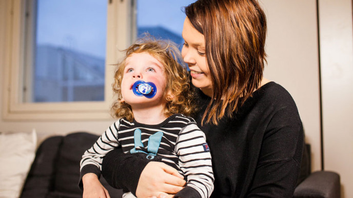 Tutti suussa oleva lapsi äidin sylissä. Kuvituskuva.