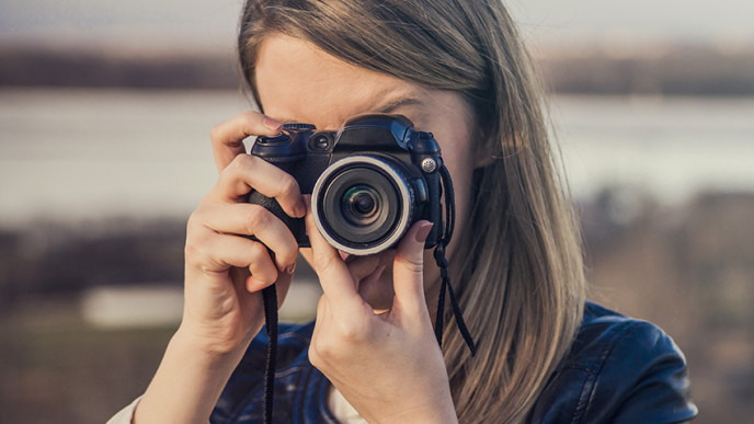 Nainen kuvaa kameralla.