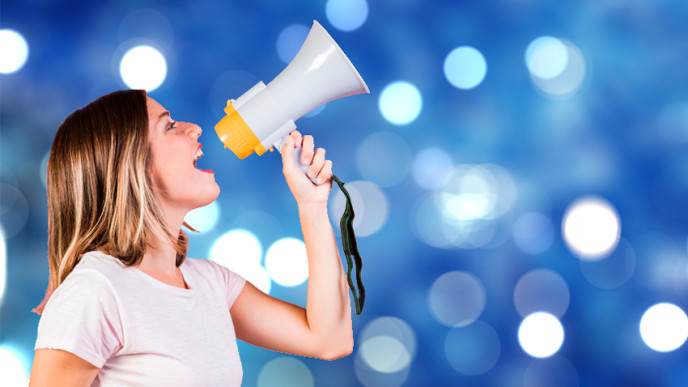 Nuori nainen kuuluttaa megafoniin. Kuvituskuva. 