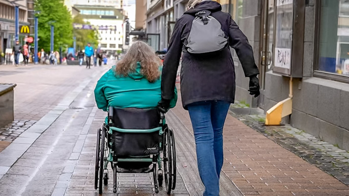 Pyörätuolilla liikkuva henkilö avustajansa kanssa kävelykadulla
